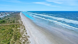 A coastal view with a beach, ocean, and a road running parallel to the shore. - Modern Oceanview Condo With Multiple Balconies, Pool & W/D - Beach Access (St. Augustine)