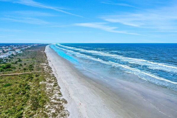 A coastal view with a beach, ocean, and a road running parallel to the shore. - Modern Oceanview Condo With Multiple Balconies, Pool & W/D - Beach Access (St. Augustine)