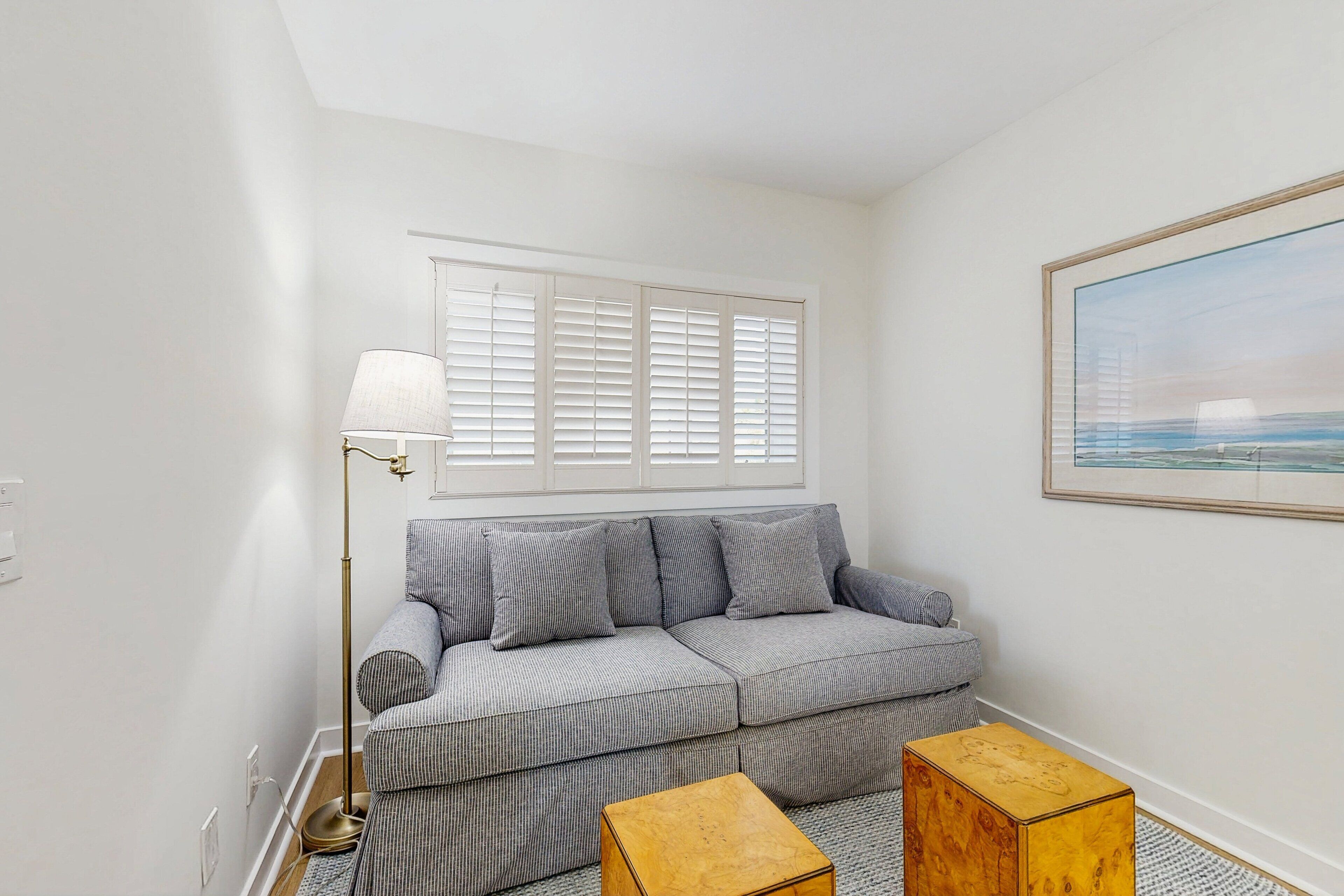 A modern living room with a grey sofa, a floor lamp, and a framed picture on the wall.