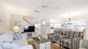Un salon comprenant un canapé, des fauteuils, une table basse, un téléviseur et un ventilateur de plafond.