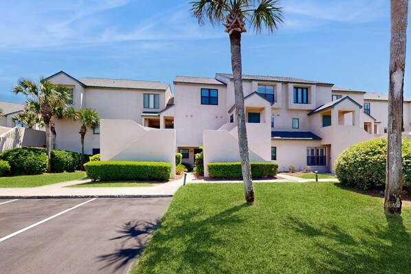 A modern multi-story residential building with a symmetrical facade, multiple windows, and a central entrance. - Newly Decorated, Oceanfront Townhouse With Patio, Wifi, W/D & Shared Pool (Fernandina Beach)
