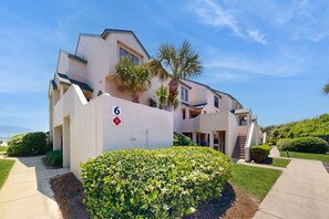 A modern two-story building with a flat roof, a number '6' sign, and a well-maintained lawn with a hedge in the foreground. - Newly Decorated, Oceanfront Townhouse With Patio, Wifi, W/D & Shared Pool (Fernandina Beach)