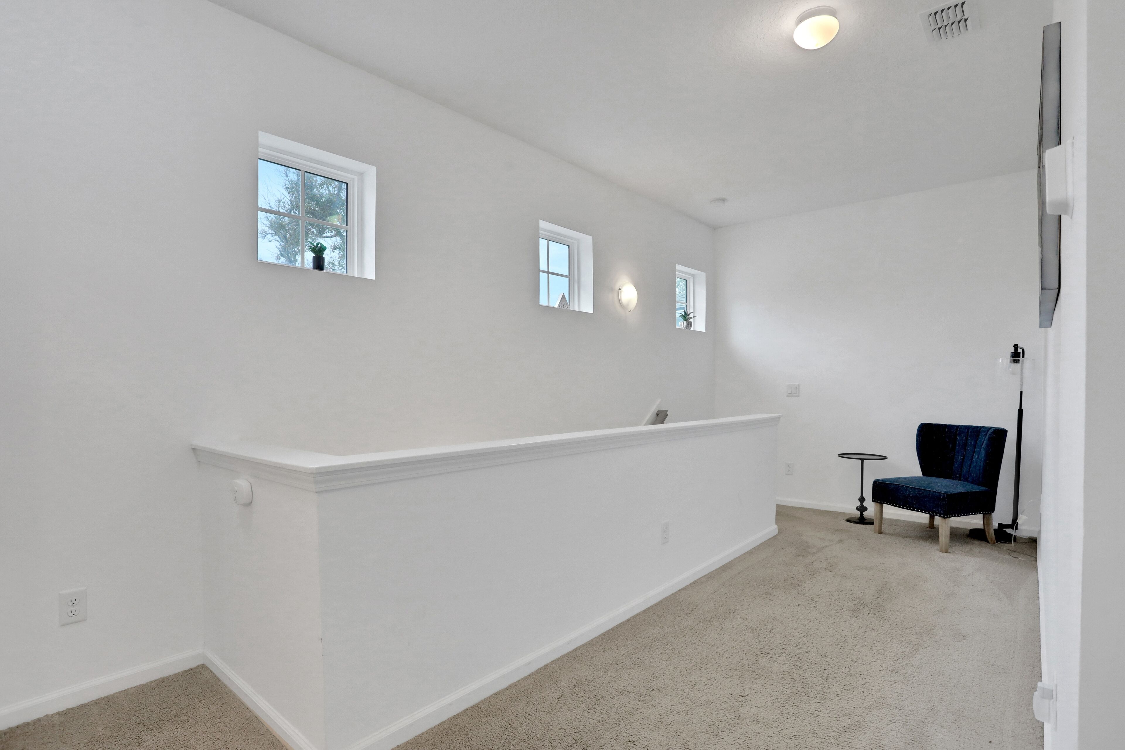 A spacious room with white walls, a built-in bench, and a blue chair.