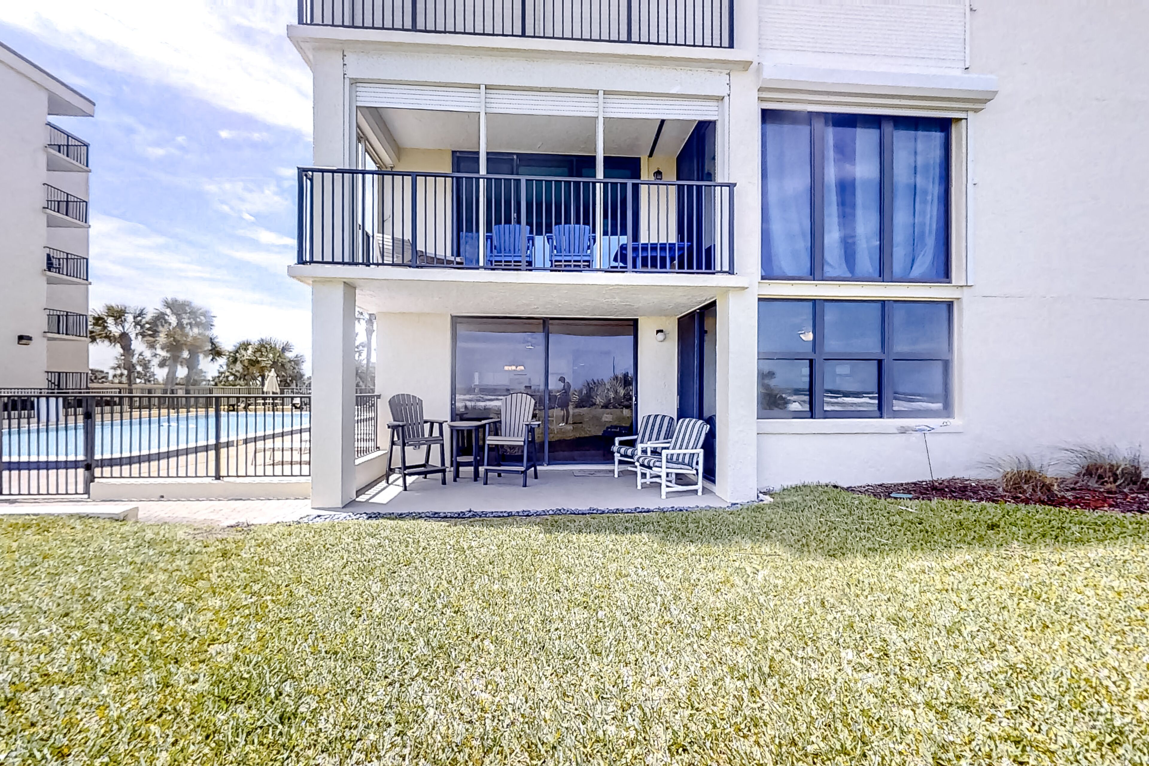 A multi-story building with a balcony, outdoor seating, and a pool.