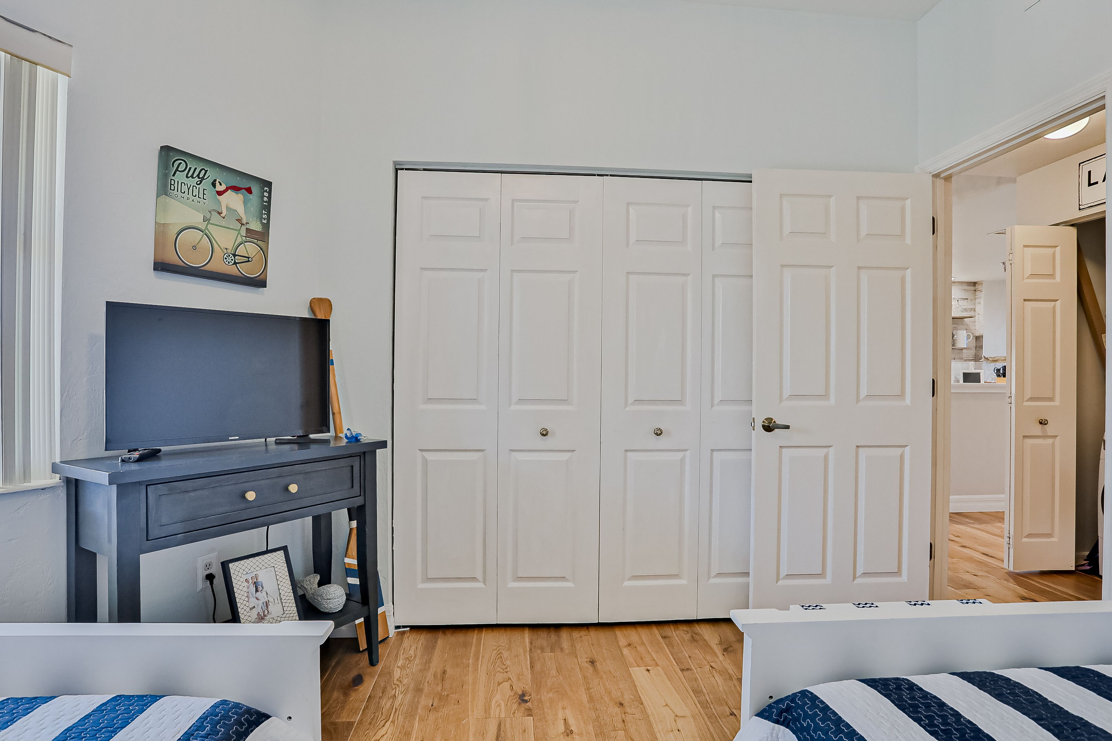 Een slaapkamer met een bed, een bureau, een kledingkast en een deur naar een andere kamer.