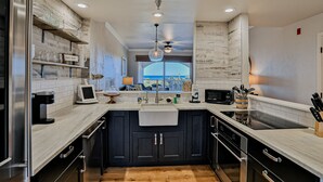 A modern kitchen with dark cabinets, a white countertop, a built-in oven, and a window with a view. - Ocean View Condo With Pool Access, Wifi, & Central AC - Snowbirds OK (Palm Coast)