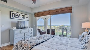 A bedroom with a large bed, a dresser, a television, and a balcony with a view of the outdoors. - Ocean View Condo With Pool Access, Wifi, & Central AC - Snowbirds OK (Palm Coast)