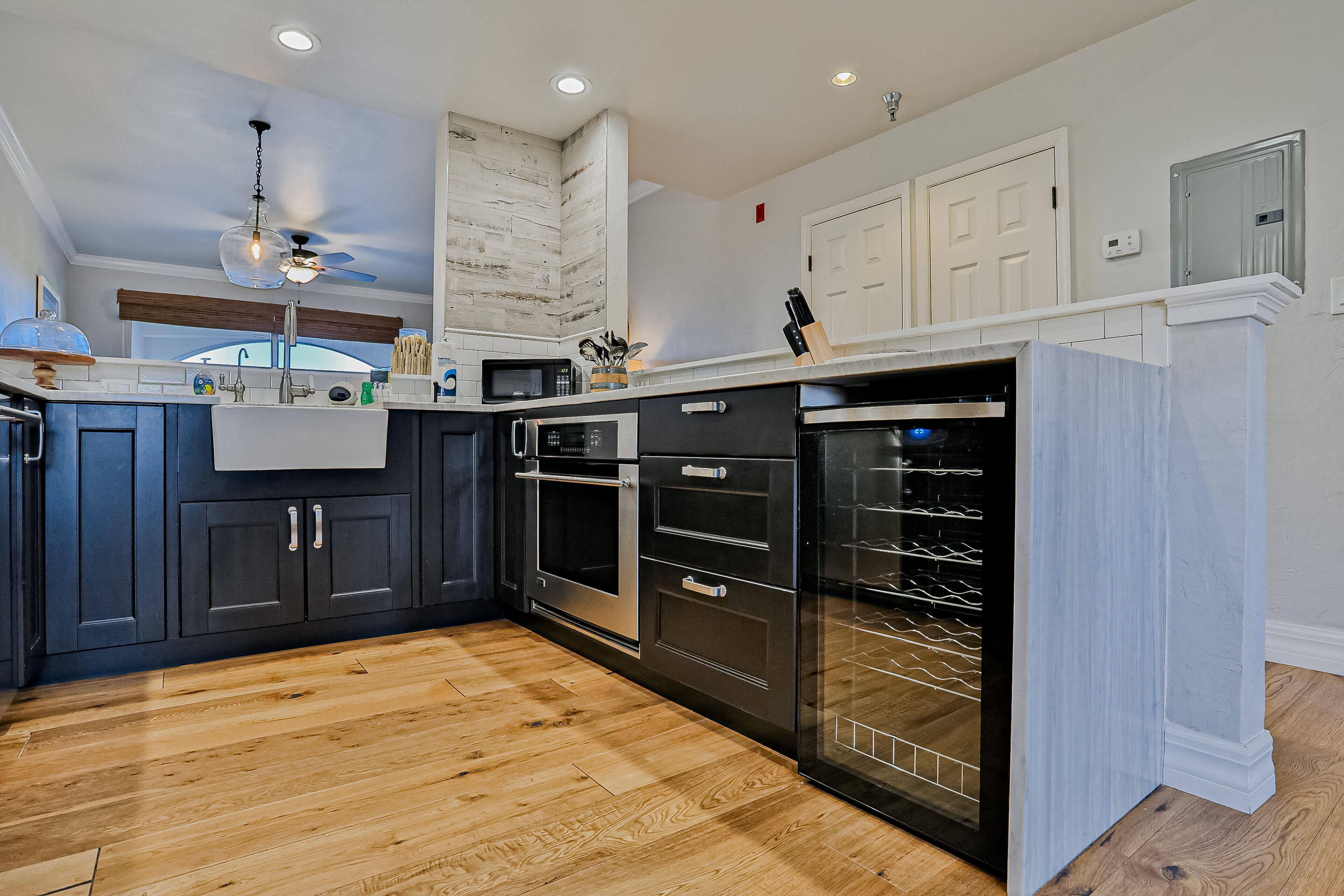 A modern kitchen with dark blue cabinets, stainless steel appliances, and a wooden floor.
