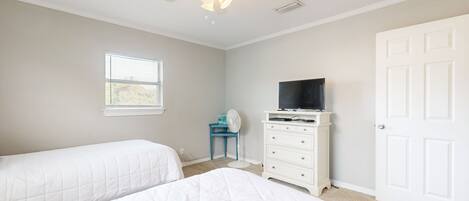 A bedroom with two beds, a ceiling fan, a dresser, a television, and a window.