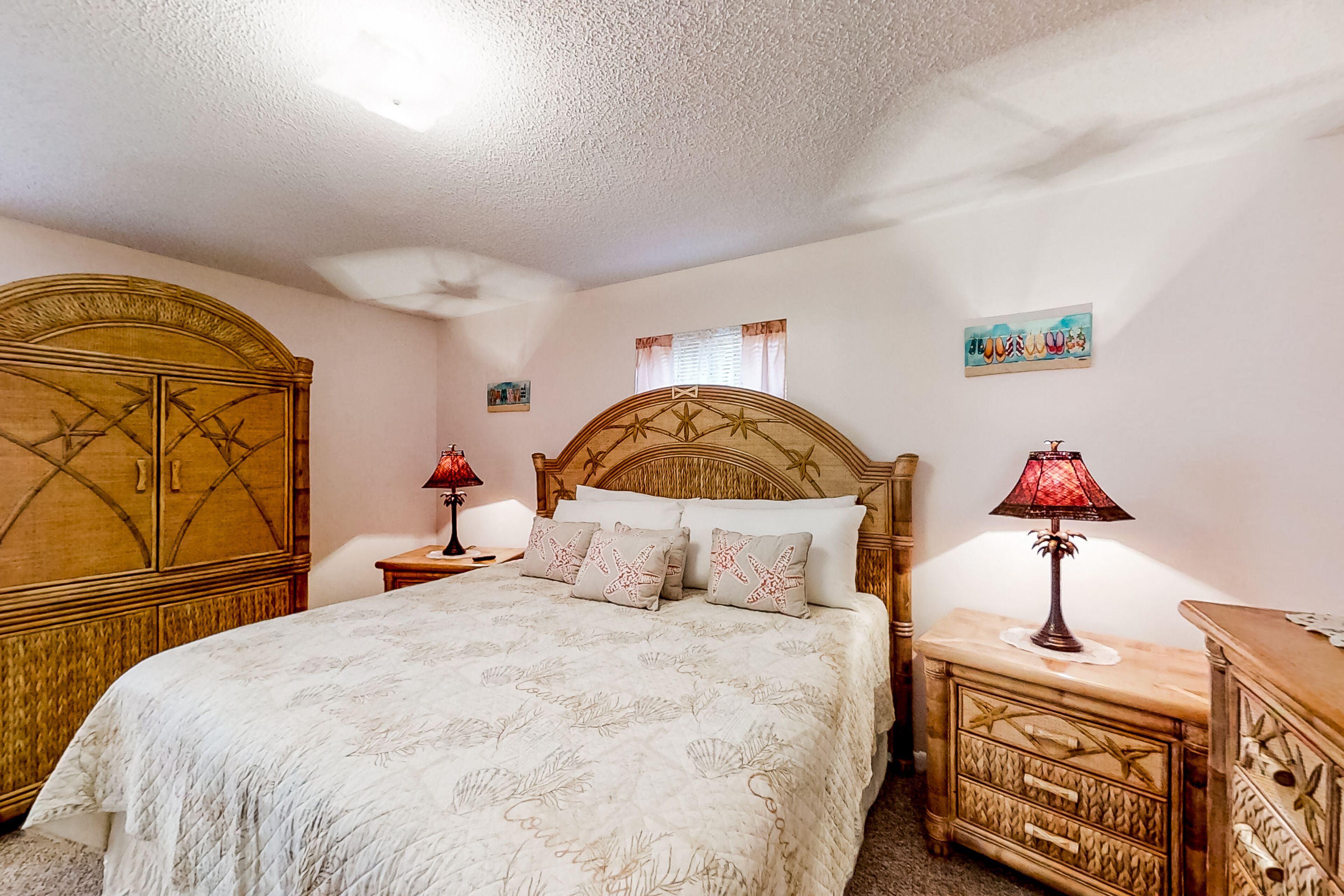A bedroom with a large bed, wooden headboard, two bedside tables with lamps, and a wooden dresser.