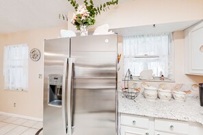 A modern kitchen with stainless steel appliances, a water dispenser, and decorative items on the counter. - Jacksonville's Delight House in Jacksonville With Pool on St Johns River (Jacksonville)