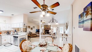 A spacious kitchen with white cabinets, a dining area with wicker chairs, and a ceiling fan. - Jacksonville's Delight House in Jacksonville With Pool on St Johns River (Jacksonville)