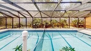 An indoor swimming pool with a glass ceiling, surrounded by plants and a wooden fence. - Jacksonville's Delight House in Jacksonville With Pool on St Johns River (Jacksonville)
