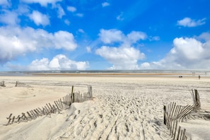 A wide sandy beach with wooden fences and footprints. - Island-themed Living With Furnished Patio, Shared Pool & Beach Access (St. Augustine)