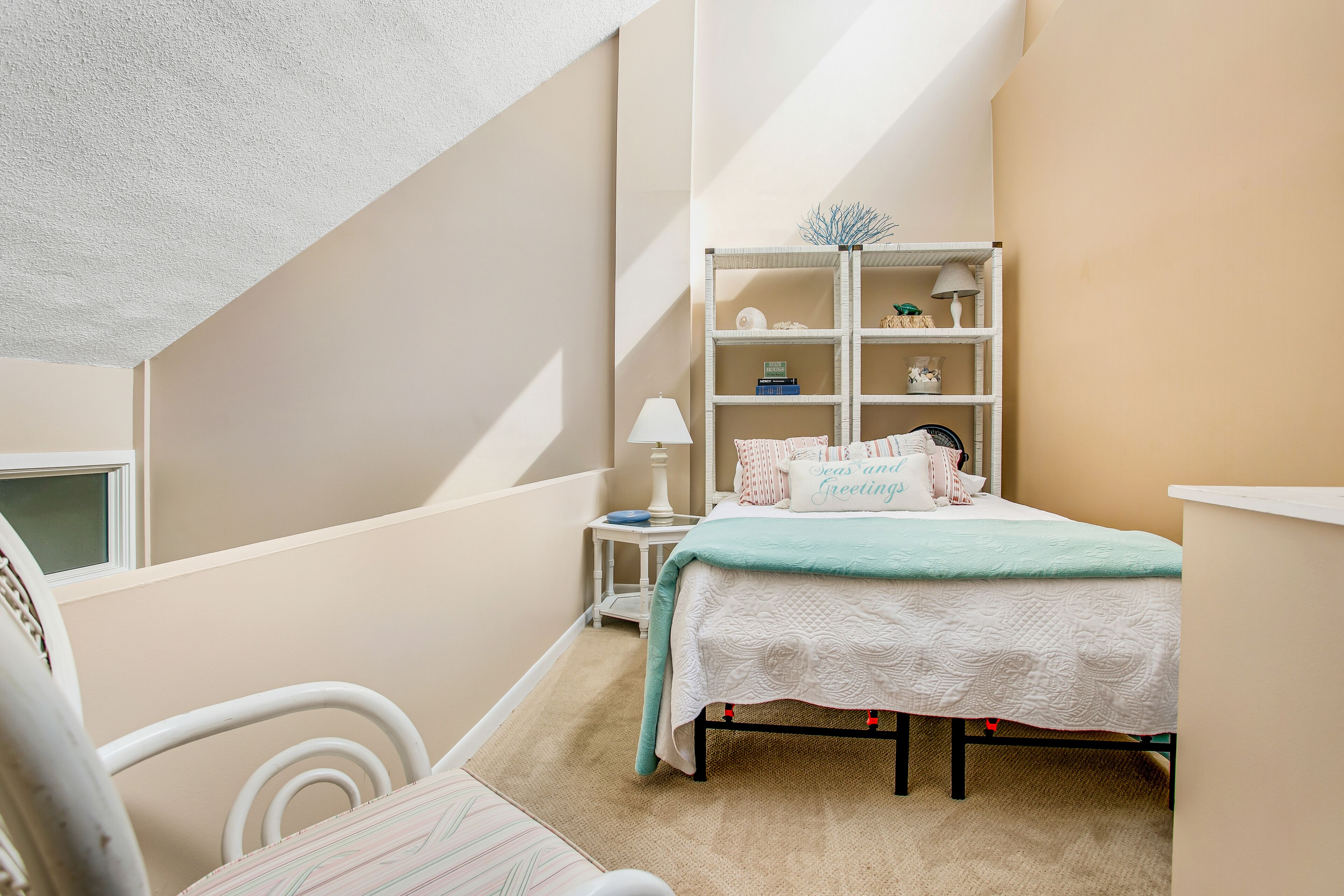 A bedroom with a bed, a nightstand, a lamp, and a bookshelf.