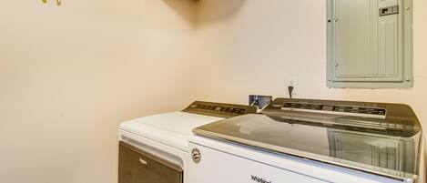 A compact, white Whirlpool washer and dryer unit in a laundry room with a wall-mounted butterfly decoration.