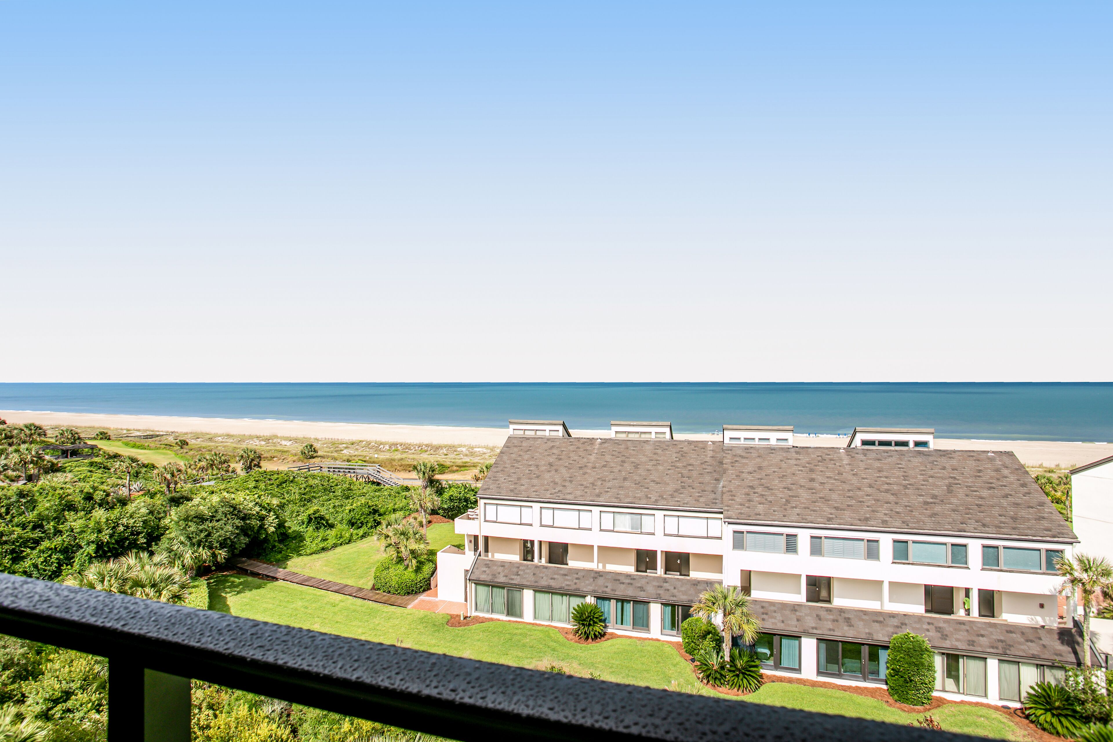 A two-story building with a flat roof, large windows, and a view of the beach.