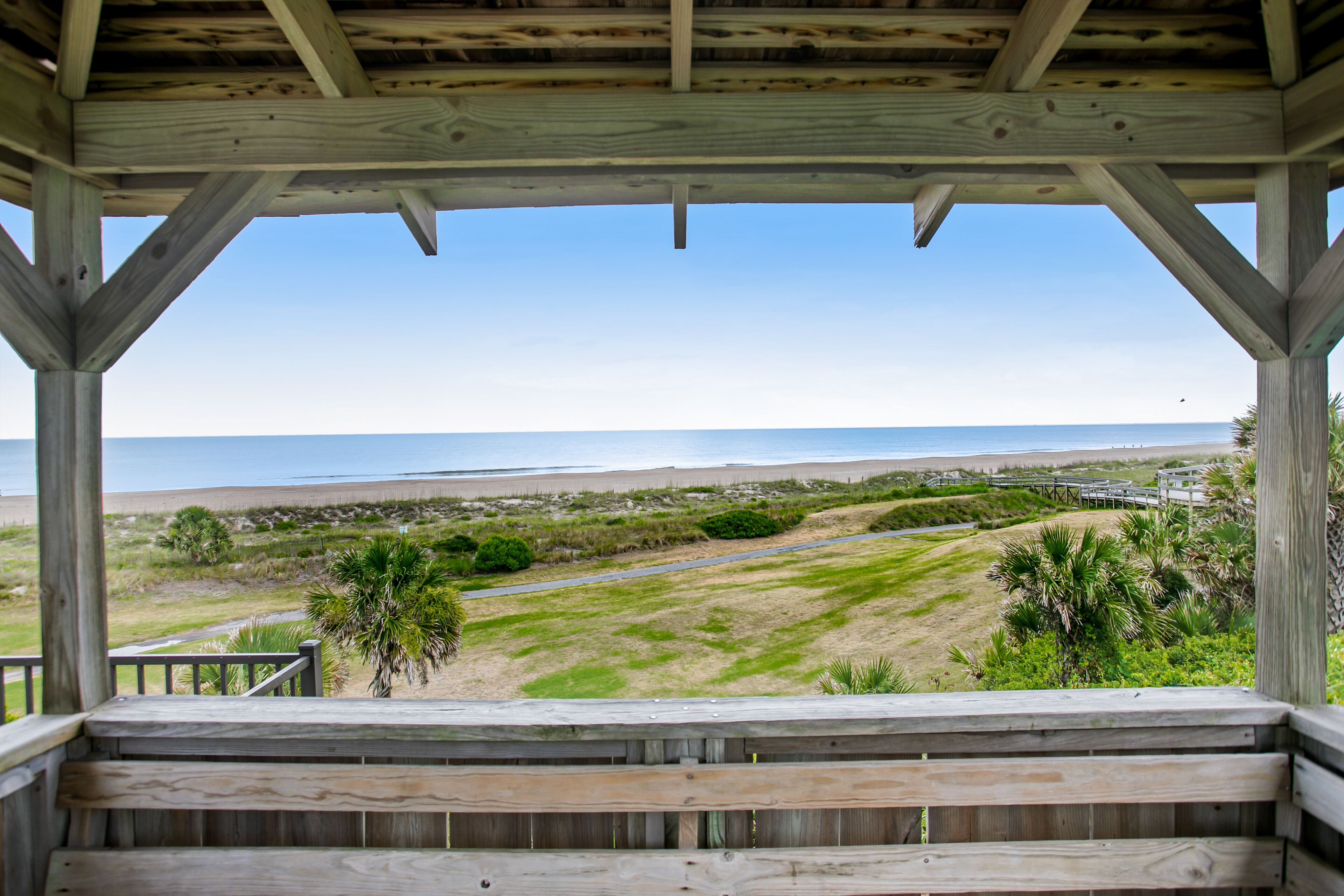 A wooden deck with a view of a beach and dunes.