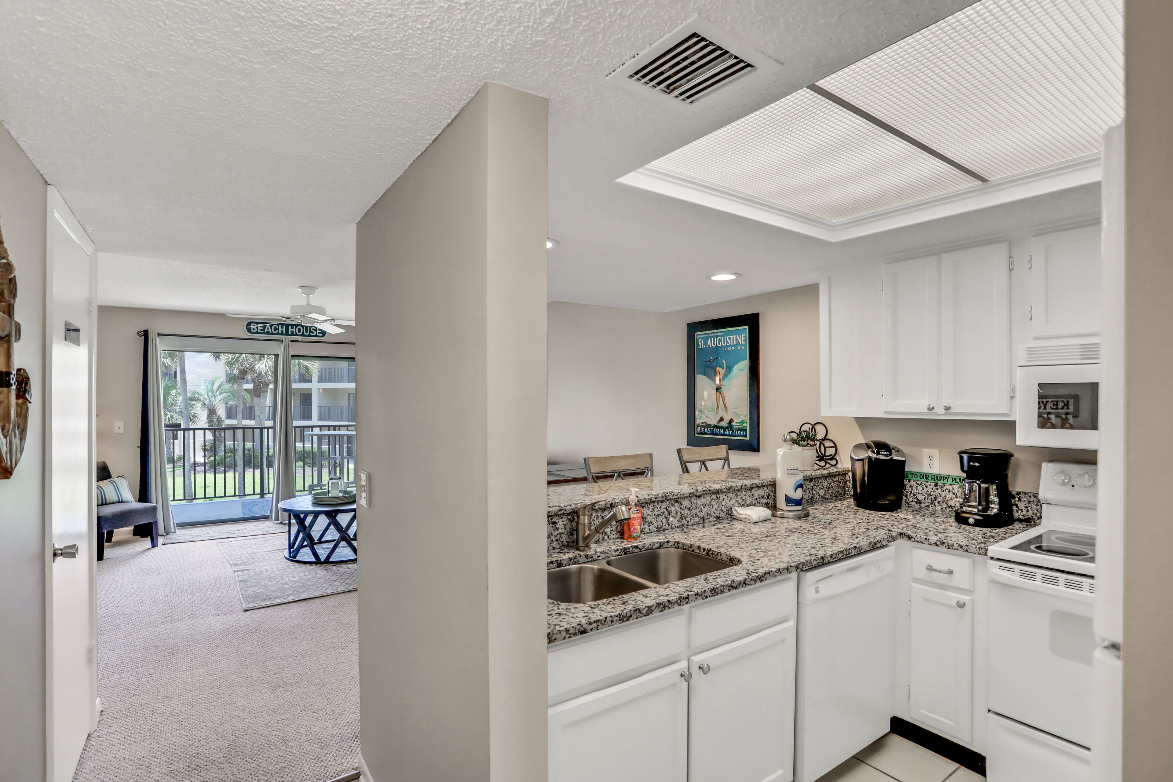 A modern kitchen with white cabinets, granite countertops, and stainless steel appliances.