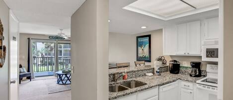 A modern kitchen with white cabinets, granite countertops, and stainless steel appliances.