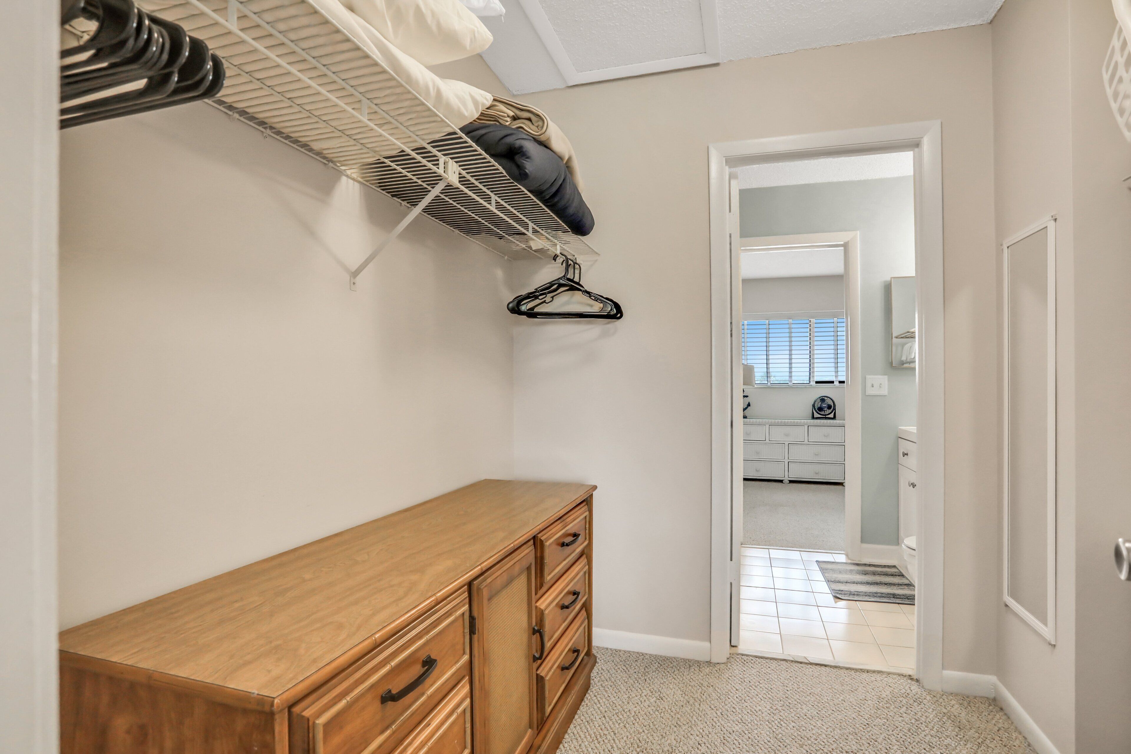 Un dormitorio con un aparador de madera, un perchero y vistas al baño.