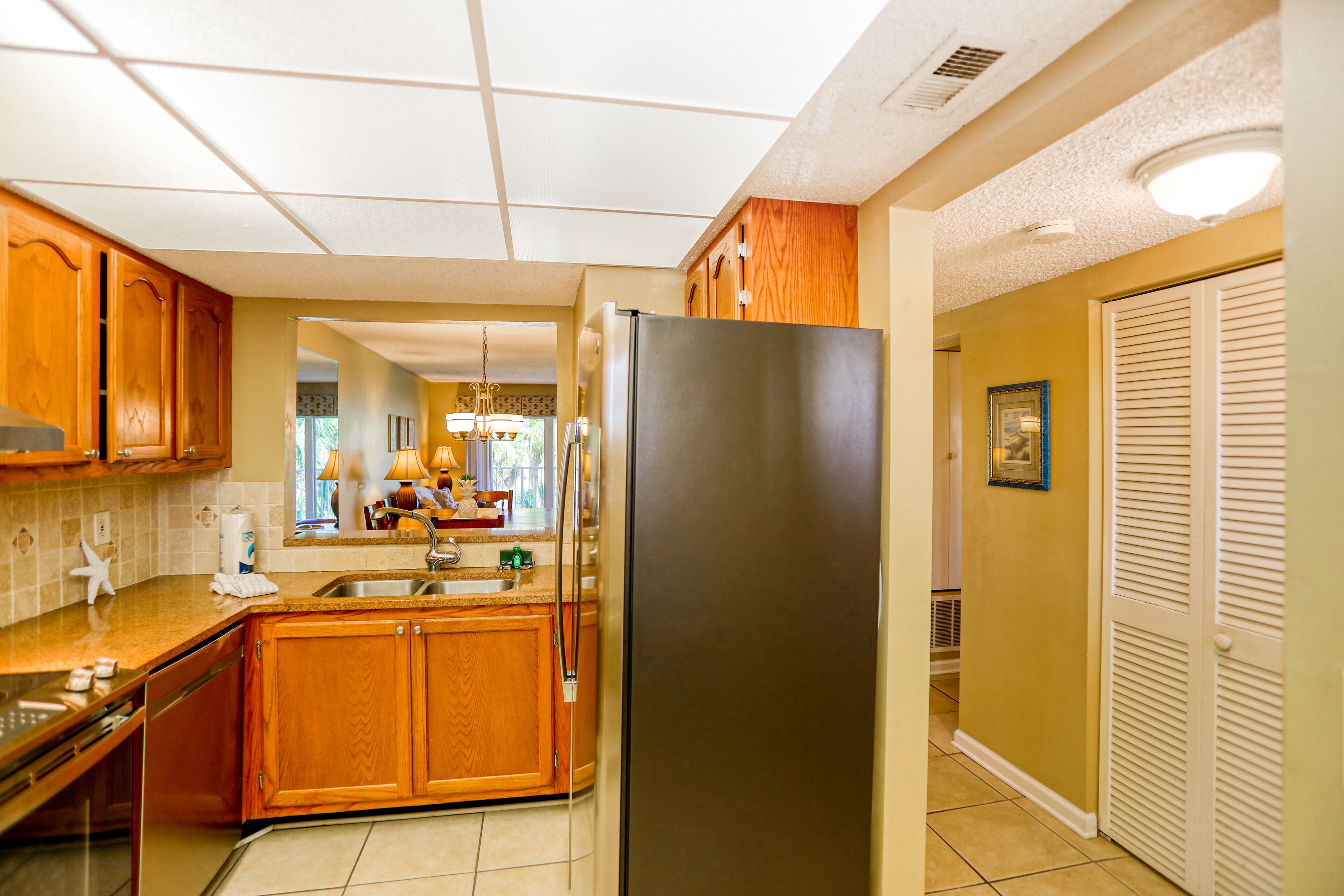 A kitchen with wooden cabinets, a stainless steel refrigerator, and a tiled backsplash.