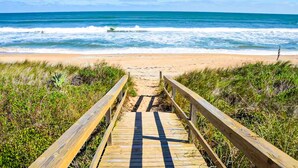 A wooden boardwalk leading to a beach with waves in the background. - Gorgeous Coastal Getaway With Large Yard, Firepit, & Screened Porch (Fernandina Beach)