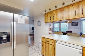 Una cocina con armarios de madera, un refrigerador, un lavavajillas y un dispensador de agua.