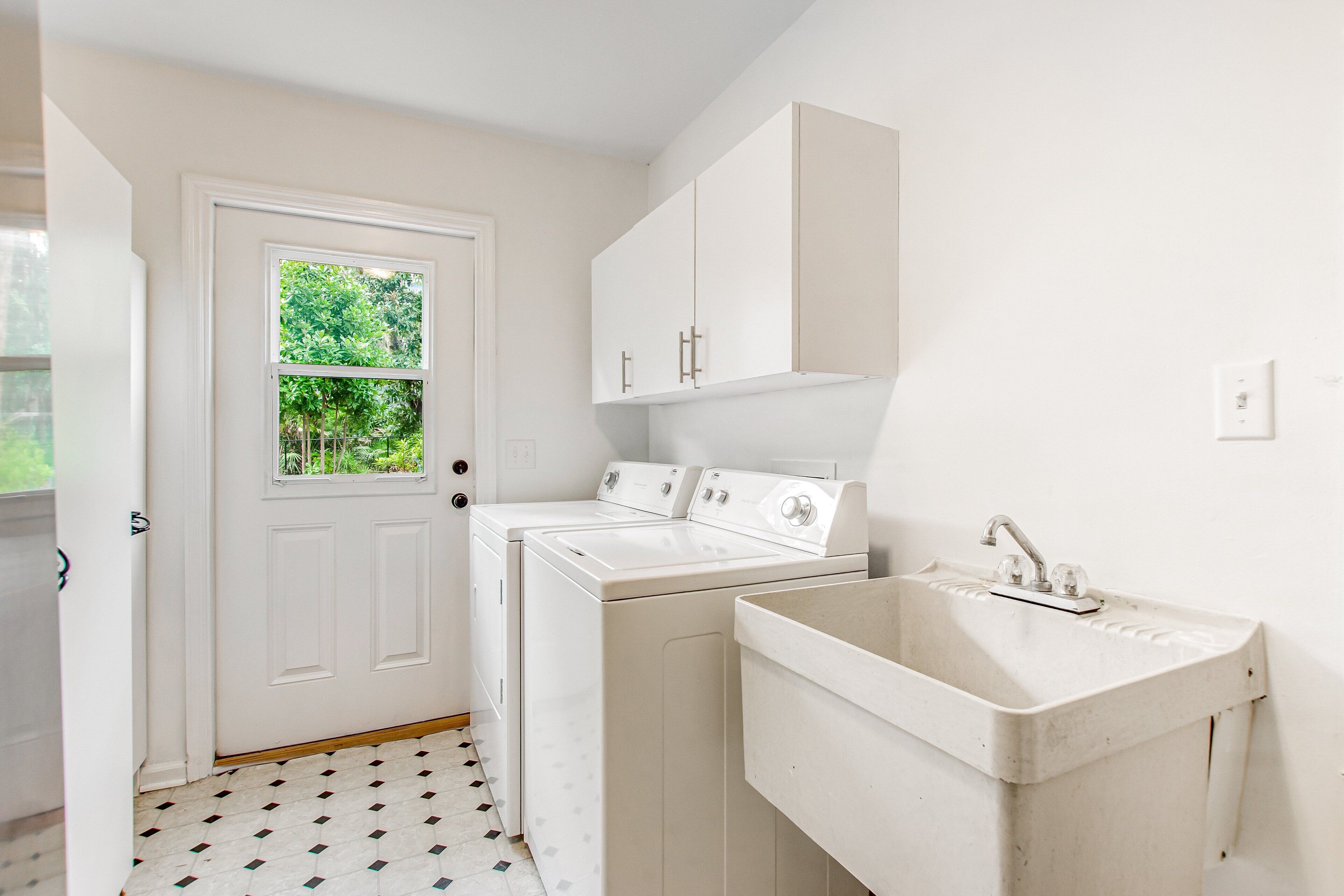 A laundry room with a door, a washing machine, a dryer, and a sink.