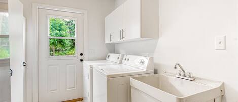 A laundry room with a door, a washing machine, a dryer, and a sink.