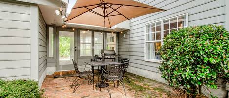 A patio with a brick floor, a table with chairs, and a large umbrella.