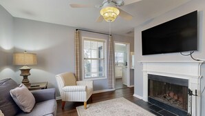 A living room with a sofa, armchair, fireplace, television, and ceiling fan. - Private Retreat With Access to Community Pool & Nearby Entertainment (St. Simons Island)