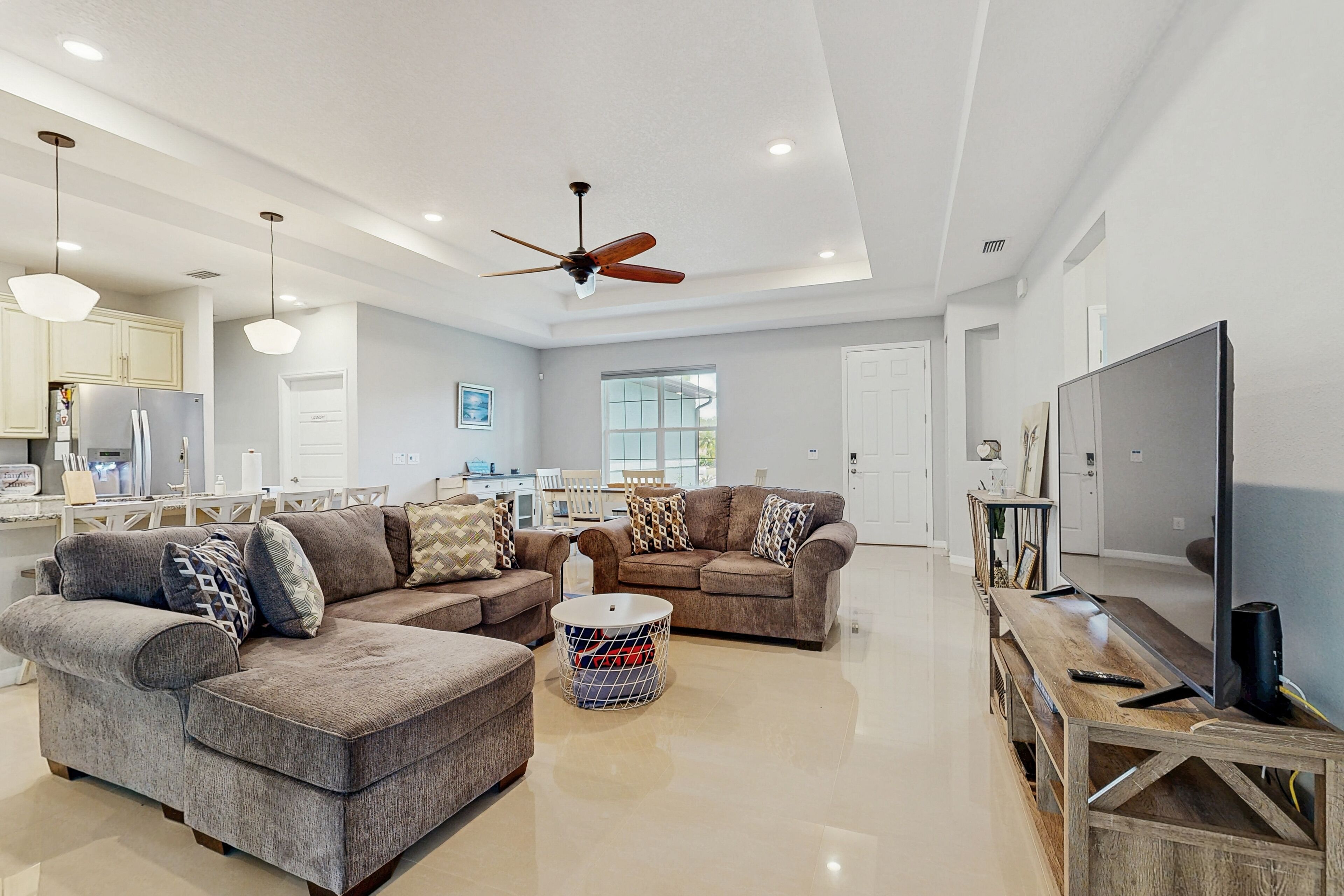 A spacious living room with a large sectional sofa, a coffee table, and a TV on a wooden stand.