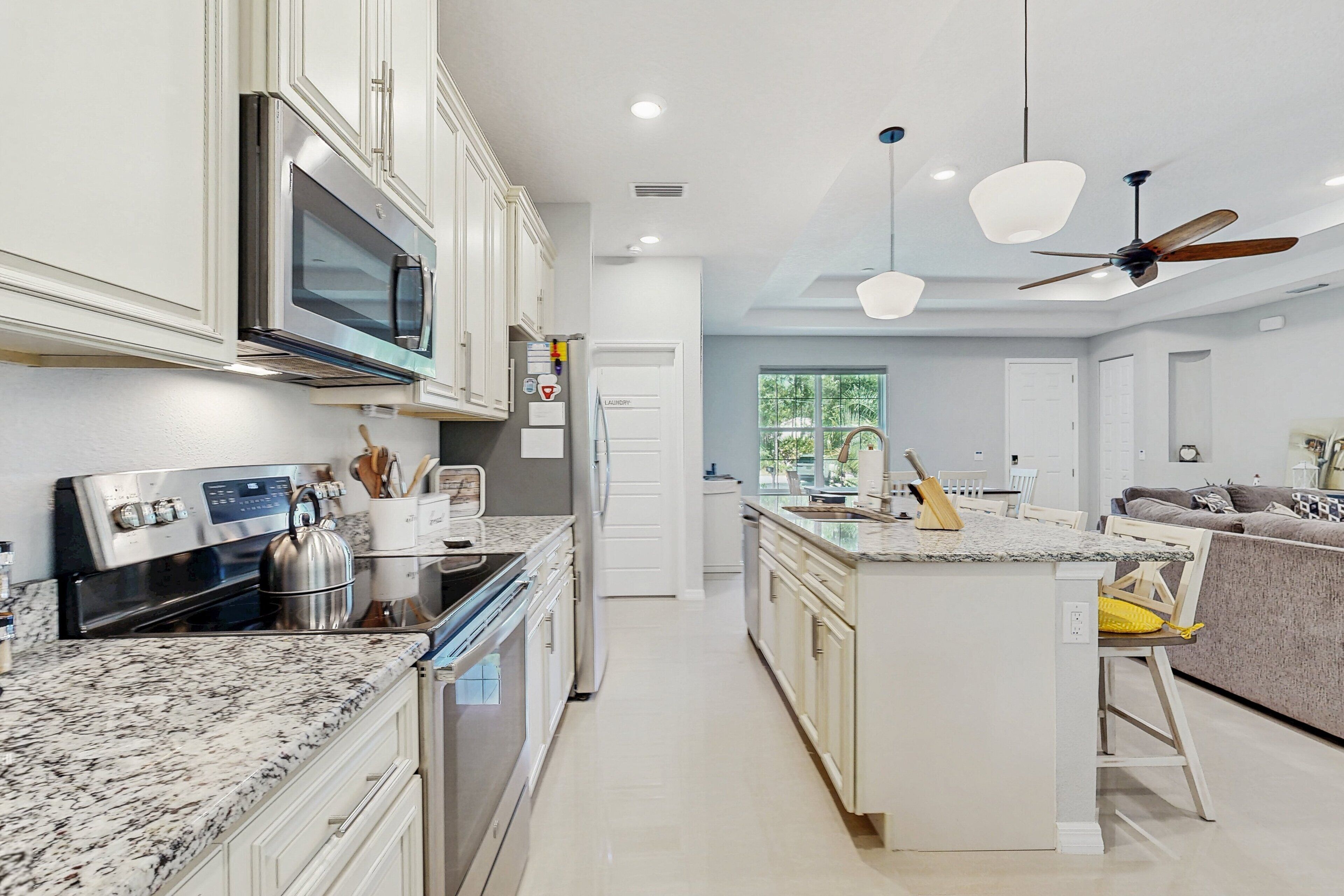 A modern kitchen with white cabinetry, stainless steel appliances, and a granite countertop.
