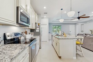 A modern kitchen with white cabinetry, stainless steel appliances, and a granite countertop. - Spacious House With Private Covered Patio, Work Station, Full Kitchen and Grill (Palm Coast)