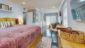 Quarto com uma cama grande, uma escrivaninha e uma cesta de vime.