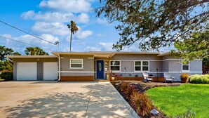 Une maison à deux étages avec une porte d’entrée bleue, un garage et une pelouse bien entretenue.