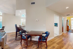 A spacious living area with a wooden floor, a dining table with chairs, and a kitchen visible in the background. - Spacious Condo With Pool, hot tub and Private Washer/dryer (St. Augustine)