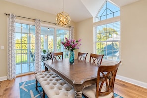 A dining room with a wooden table, six chairs, a vase with flowers, and a chandelier. - Spacious Condo With Pool, hot tub and Private Washer/dryer (St. Augustine)