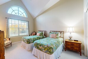 A bedroom with two beds, a nightstand, a chair, a window with curtains, and a lamp. - Spacious Condo With Pool, hot tub and Private Washer/dryer (St. Augustine)