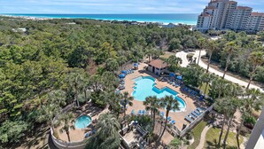 Een resort met een groot zwembad, palmbomen en uitzicht op de oceaan.