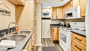 Une cuisine avec des meubles en bois, un évier en acier inoxydable, un four à micro-ondes et une cuisinière.