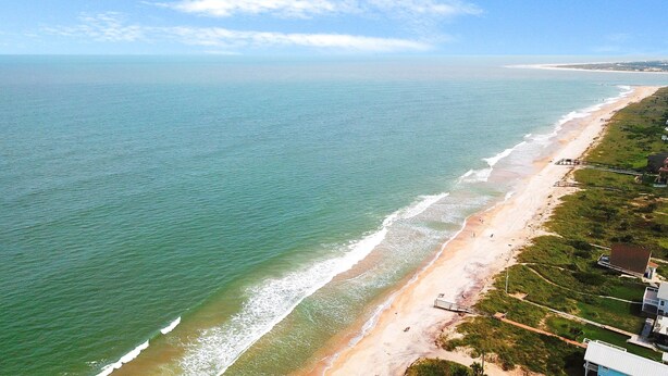 Une vue côtière comprenant une plage, l’océan et des bâtiments le long du rivage.