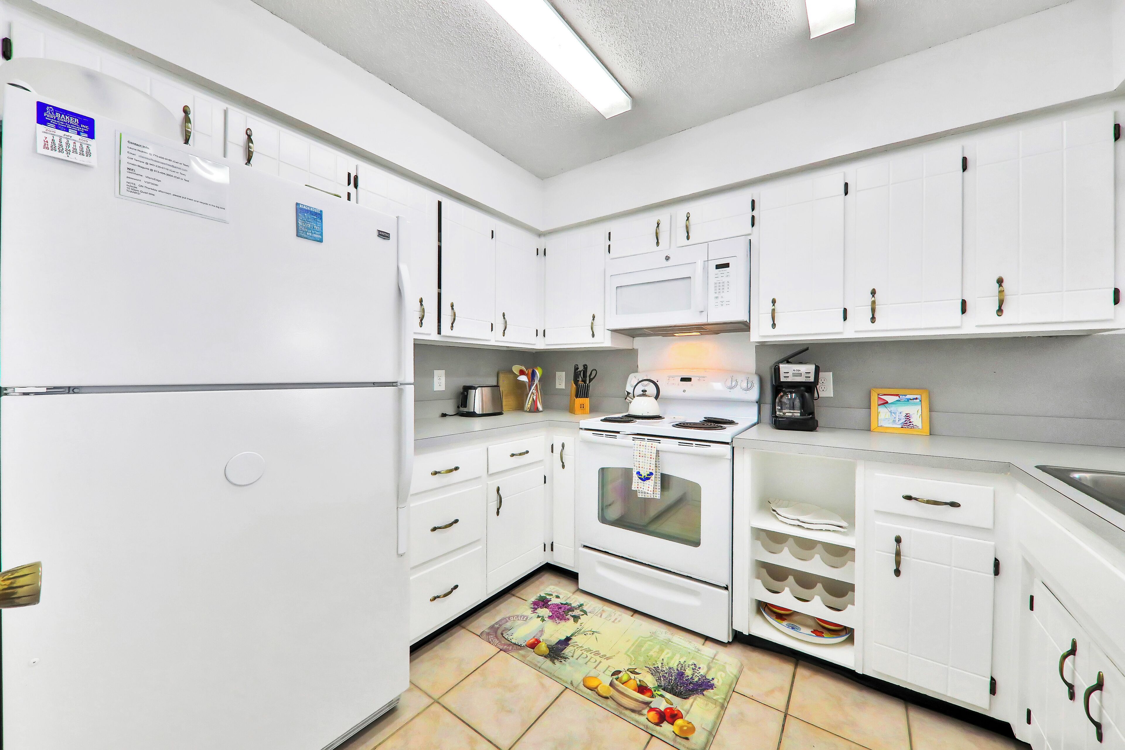 Une cuisine avec des armoires blanches, un réfrigérateur, une cuisinière et un four à micro-ondes.