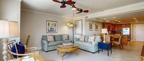 A spacious living room with a sectional sofa, a coffee table, and a ceiling fan.