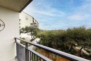 A balcony with a view of a building and trees. - Renovated Condo With Balcony, Lush Views, Outdoor Pool (Fernandina Beach)