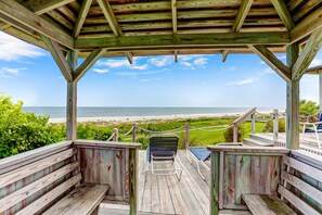 Une terrasse en bois avec des bancs donnant sur une plage.