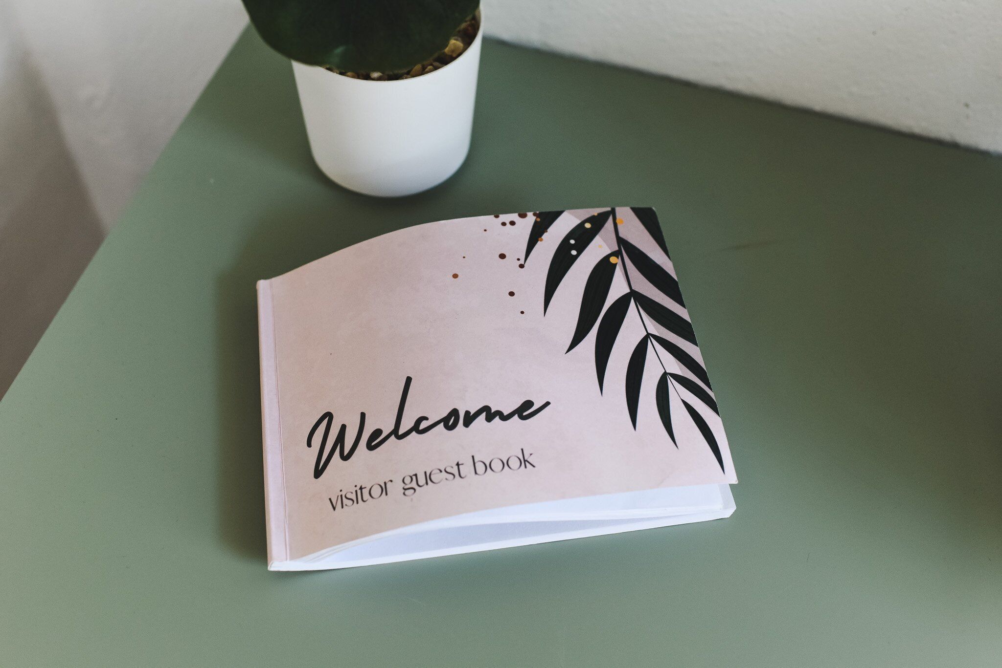 Un libro de visitas de bienvenida sobre una mesa verde.