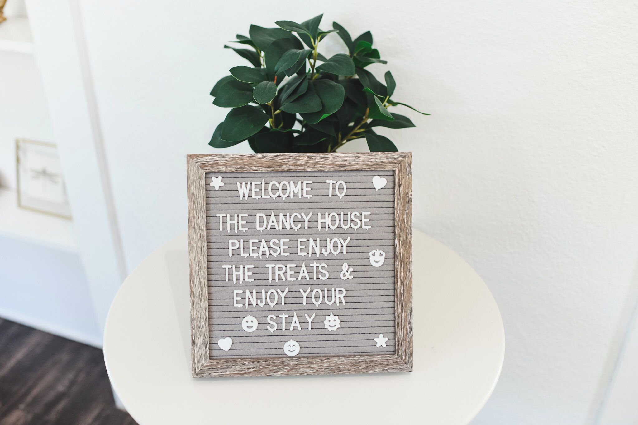 A welcome sign with a rustic wooden frame and a message inviting guests to the Dancy House.