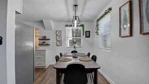 A dining area with a wooden table, black chairs, and woven placemats. - Downtown Jacksonville Retreat Pet-friendly With Hot Tub & Backyard Oasis (Jacksonville)